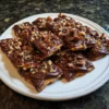 Delicious homemade chocolate-covered cracker candy, a perfect christmas crackers chocolate recipe, piled high on a white ceramic plate.