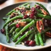 Vibrant close-up of a Christmas green beans recipe featuring cranberries and pecans on a light plate.