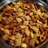 Overhead view of a delicious Christmas Chex Mix recipe in a polished metal bowl, featuring glazed Chex cereal, pretzels, nuts, and savory crisps, perfect for holiday snacking.