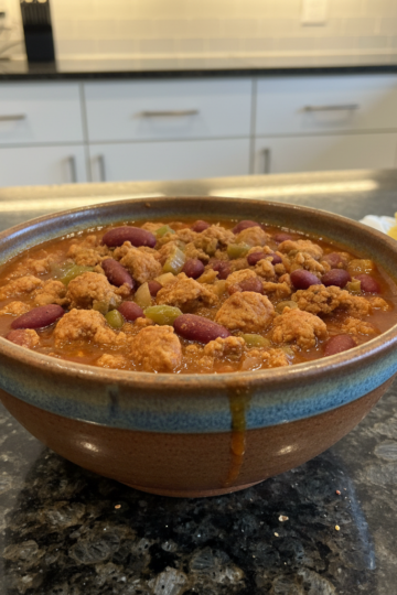 A hearty bowl of ground turkey chili topped with cheese and cilantro, ready to be enjoyed.