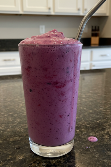 A vibrant, creamy probiotic berry smoothie in a tall glass with fresh berries and mint garnish.