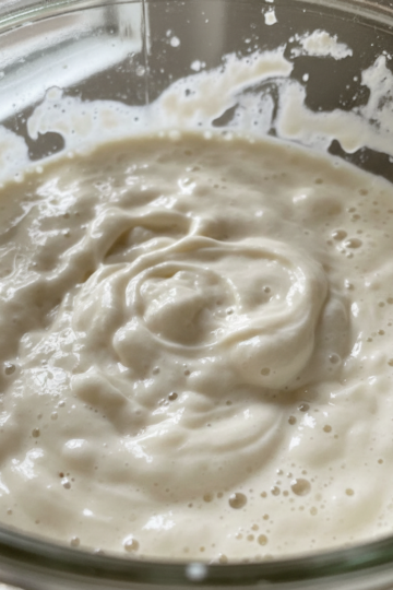 A vibrant, bubbly sourdough bread starter in a glass jar, showing its active, ready-to-use state.