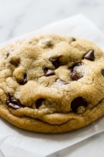 Golden chocolate chip cookies recipe using brown butter on a white marble surface with soft natural lighting.