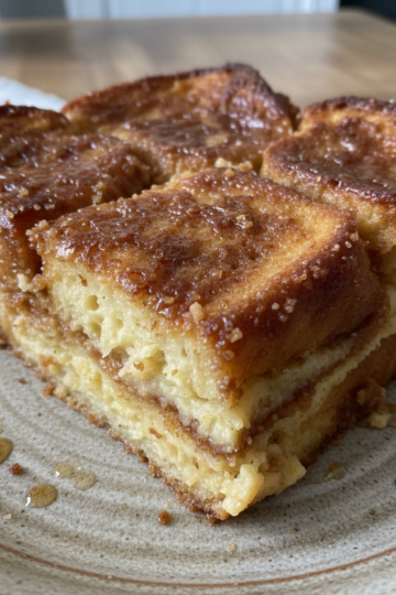 Golden brown overnight french toast casserole with powdered sugar and berries on top, ready to serve.