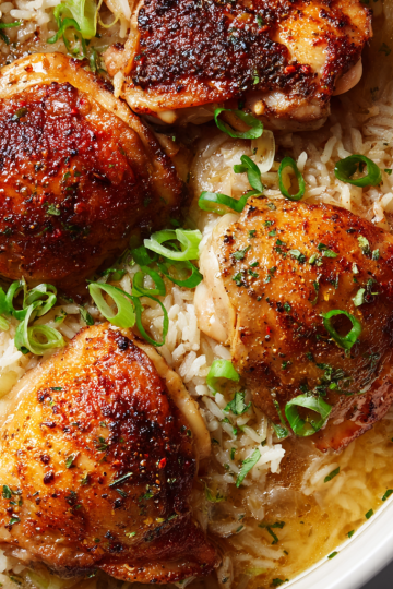 A golden-brown skillet of one-pot chicken and rice, garnished with fresh parsley, ready to be served.