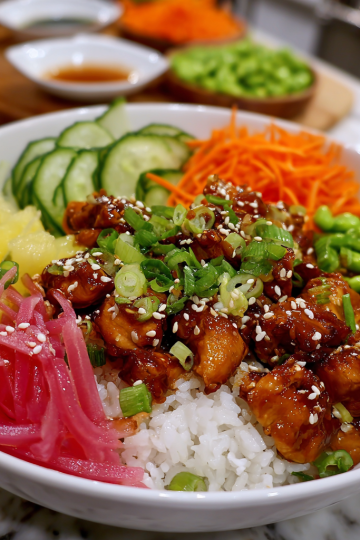 A vibrant Sticky Chicken Poke Bowl featuring glazed chicken, fresh avocado, edamame, and rice, ready to eat.